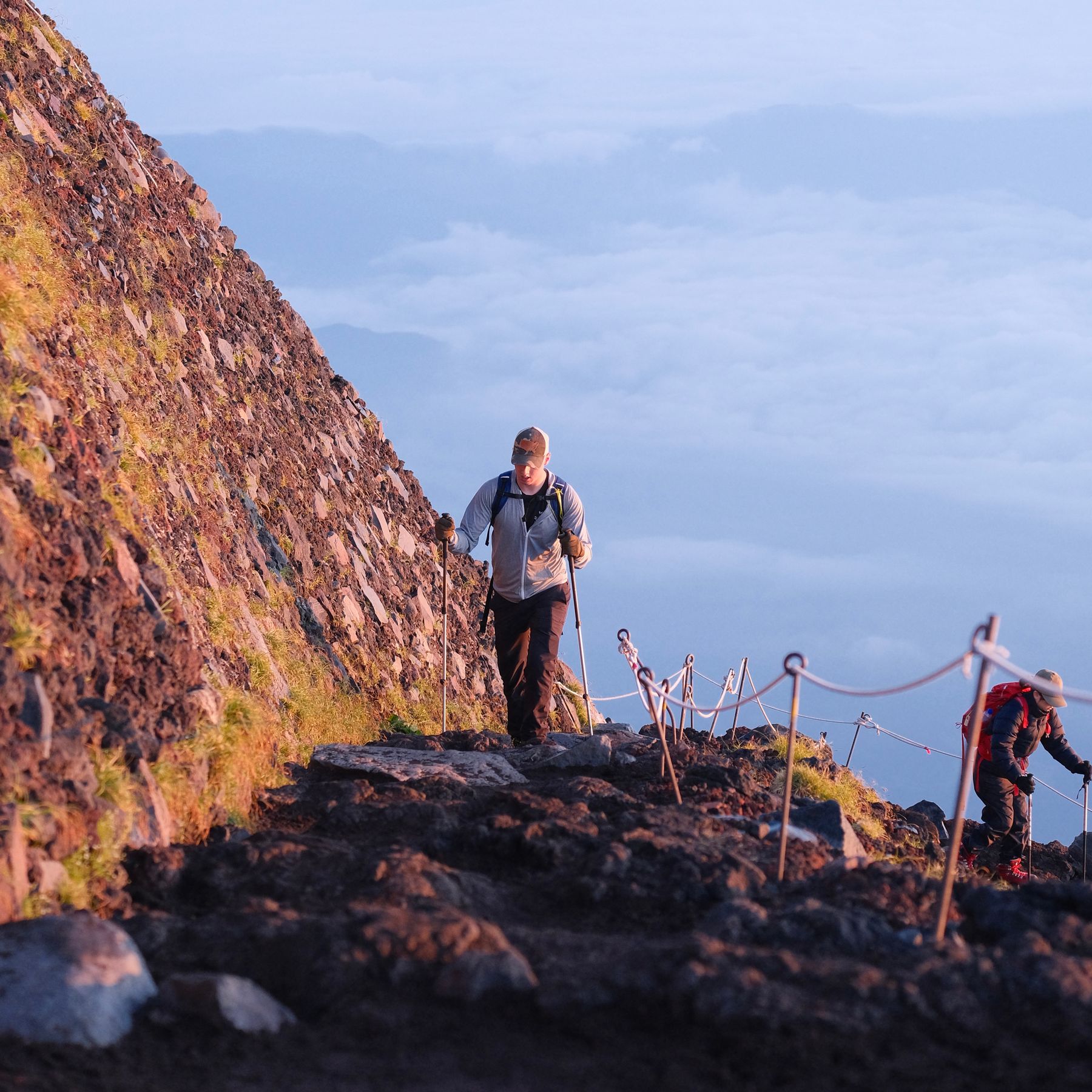 Two climbers on the upper slope of Mount Fuji in early morning light