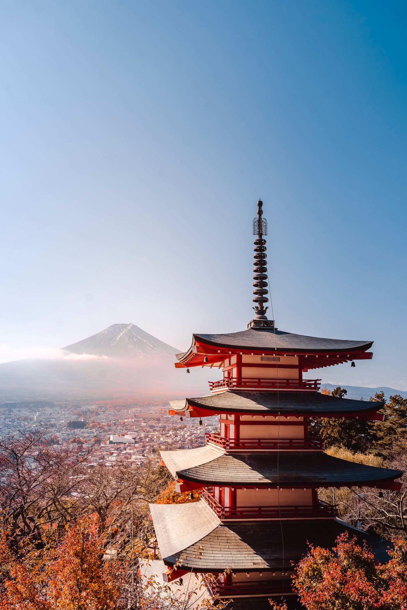 A red pagoda above autumn maples with Mount Fuji beyond