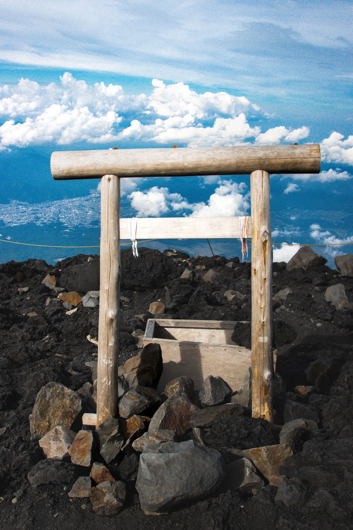 A weathered wooden torii gate on the rocky summit of Mount Fuji